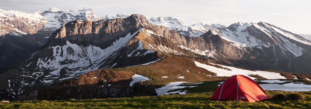 A tent below snowy mountain peaks